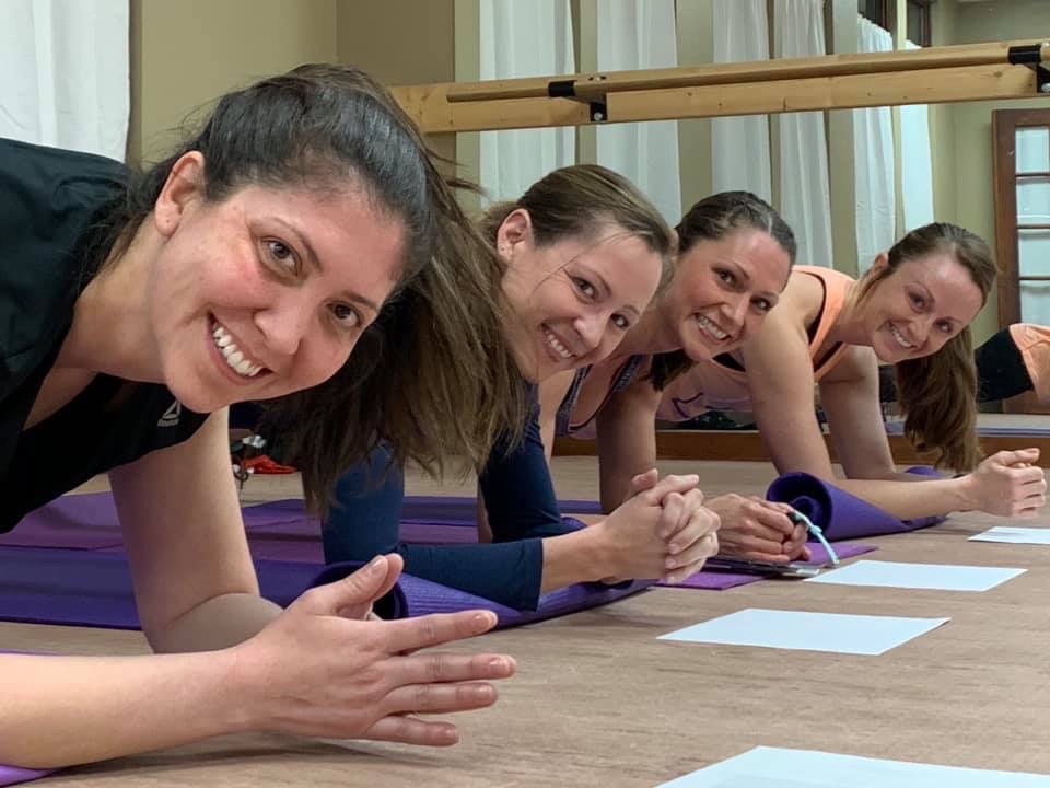 Three Women and I are in a plank position looking at the camera smiling. Pushing others and myself are amazing for my mental health. 